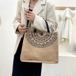 Detail van de boho jute draagtas met geometrische patronen en zwarte geweven handvatten
