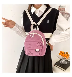 Close-up of a pink corduroy backpack featuring smiley patterns and a front flap pocket