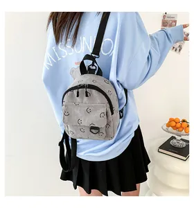 Close-up of grey corduroy mini backpack featuring smiley face pattern and adjustable straps