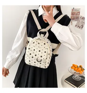 Detailed close-up of a mini white corduroy backpack with floral pattern on a female model