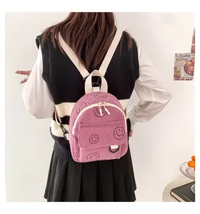 Detail of purple corduroy backpack with smiley face pattern and white fabric strap
