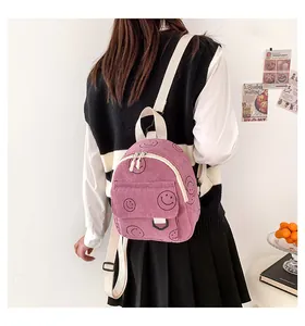 Detail of pink corduroy backpack with smiley patterns and adjustable straps