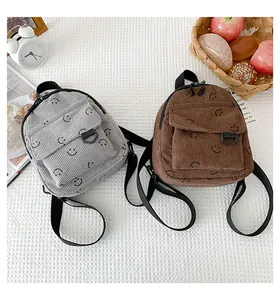 Close-up of grey and brown corduroy mini backpacks with smiley face patterns