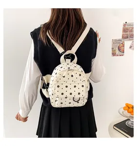 Close-up of white corduroy mini backpack featuring cute black floral patterns and straps