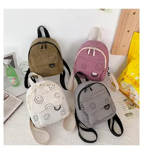 Flat lay of four colorful corduroy mini backpacks with smiley prints and casual accessories