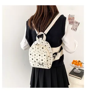 Detailed back view of a mini beige floral corduroy backpack worn by a model