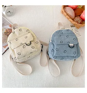 Detail view of mini corduroy backpacks in off-white and blue with smiley face pattern