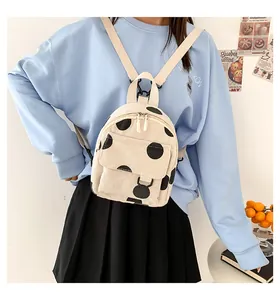 Mini corduroy backpack with black polka dots shown on model in a cozy indoor setting