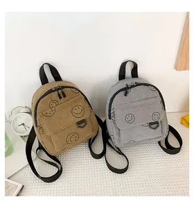 Detail view of khaki and grey corduroy mini backpacks with smiley face patterns