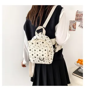 Detail of white corduroy mini backpack featuring vintage black floral patterns