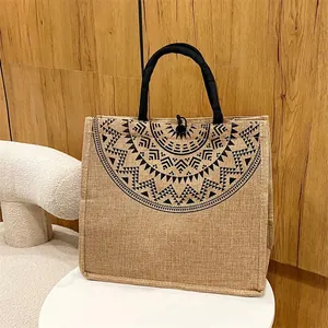 Detailweergave van natuurlijke jute shopper met zwart mandala-patroon en touwhandvatten