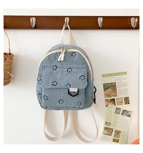 Close-up of light blue corduroy backpack with embroidered smiley faces and zip closure