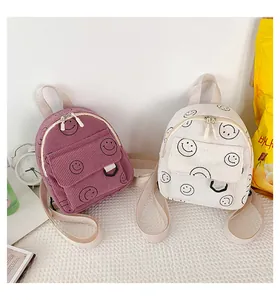 Detail of purple and beige corduroy backpacks with smiley faces and shoulder straps