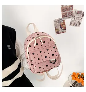 Detail of pink corduroy mini backpack with floral pattern and white straps
