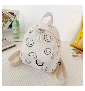 Detail of white corduroy backpack with smiley prints showing fabric texture and pockets