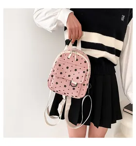 Pink corduroy mini backpack with black floral patterns shown on model in school style