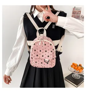 Pink corduroy mini backpack with floral pattern and white straps in a lifestyle scene