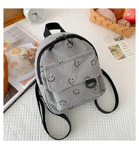 Detail of grey corduroy backpack with smiley face print and metal zippers in a lifestyle setting