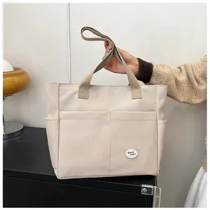 Detailed close-up of a cream canvas tote bag with multi-pocket design and lucky cloud label