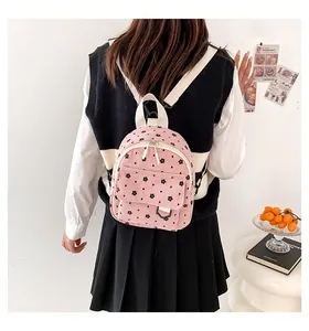 Pink corduroy mini backpack with black floral patterns and white straps for students