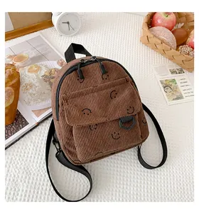 Detailed close-up of brown corduroy mini backpack with happy smiley face and adjustable straps