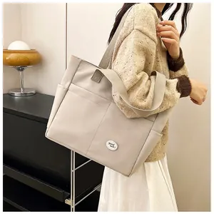 Detail of beige canvas tote bag showing multiple pockets and good luck tag on front