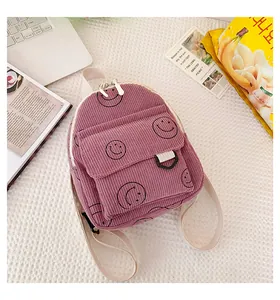 Purple corduroy backpack with smiley patterns shown in a casual lifestyle desktop setting