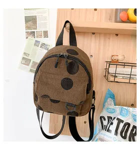 Detail of brown corduroy mini backpack with black polka dots on a wooden pegboard