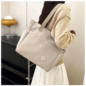 Close-up of cream canvas tote bag with front pockets and Good Luck patch detail