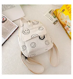Detail shot of corduroy backpack with smiley prints among lifestyle items and snacks