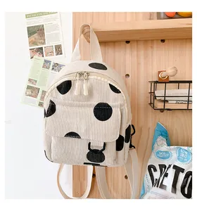 Detailed view of beige corduroy mini backpack with black polka dots on pegboard