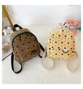 Detail of floral corduroy mini backpacks in brown and yellow on a white table