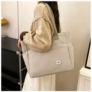 Detailed view of canvas tote bag side pocket and good luck patch on beige fabric