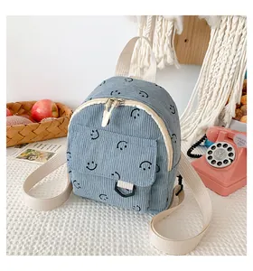 Close-up of fog blue corduroy mini backpack with black smiley faces and cream straps