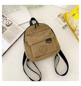 Detailed view of brown corduroy mini backpack with smiley prints and black hardware
