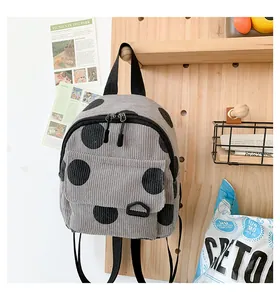Detail of grey corduroy mini backpack featuring black polka dots and front pocket design
