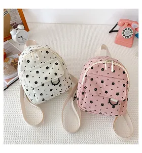 Close-up of floral corduroy mini backpacks in beige and pink with front flap pocket