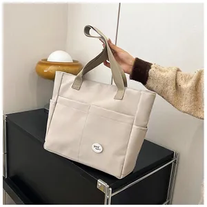 Close-up of off-white canvas tote bag with outer pockets and good luck patch detail