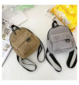 Detailed corduroy backpacks with smiley print shown in a lifestyle flat lay setting