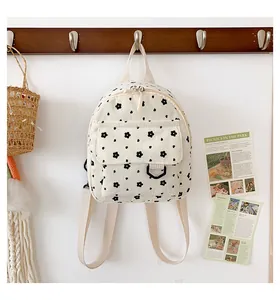 Detail of floral corduroy mini backpack with front pocket hanging on a wooden hook