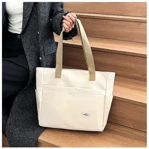 Detail of cream canvas tote bag featuring multiple pockets and a Good Luck decorative label