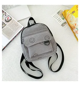 Close-up of grey corduroy mini backpack with smiley face embroidery and black straps