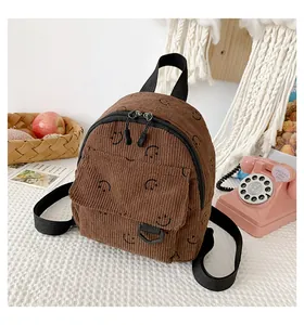 Detailed close-up of dark brown corduroy backpack with cute smiley face prints and pocket