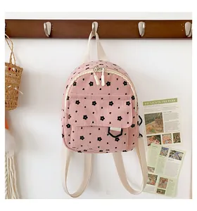 Detailed view of pink corduroy mini backpack with floral pattern on a wooden hanger