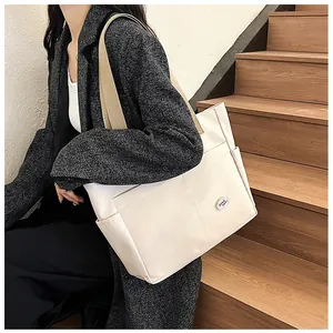 Detail of white canvas tote bag featuring outer pocket and good luck badge decoration