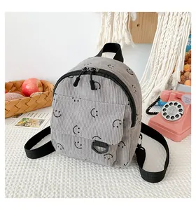 Close-up of grey corduroy backpack with smiley face pattern and small front pocket