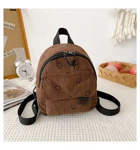 Detailed view of mini brown corduroy backpack featuring smiley face patterns and zipper