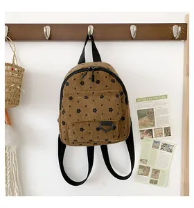 Detail of a brown corduroy backpack with small black floral patterns on a white wall