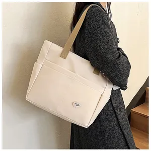Detail of minimalist cream canvas tote bag featuring multi-pockets and a good luck label