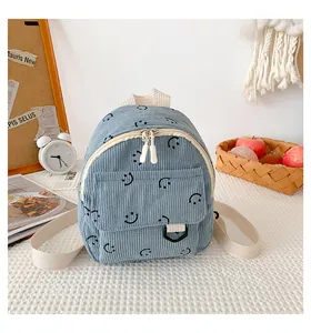 Detail of light blue corduroy backpack with smiley face print and front pocket on a table
